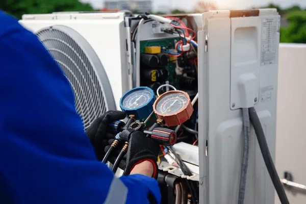Technician checking refrigerant pressures with manifold gauges